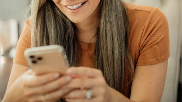 Hands using one thumb to scroll on phone.